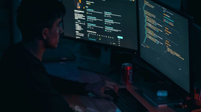 Programátor u monitorů s kódem v setmělé místnosti