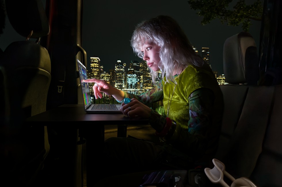 Žena pracující na MacBooku Pro za tmy v dopravním prostředku