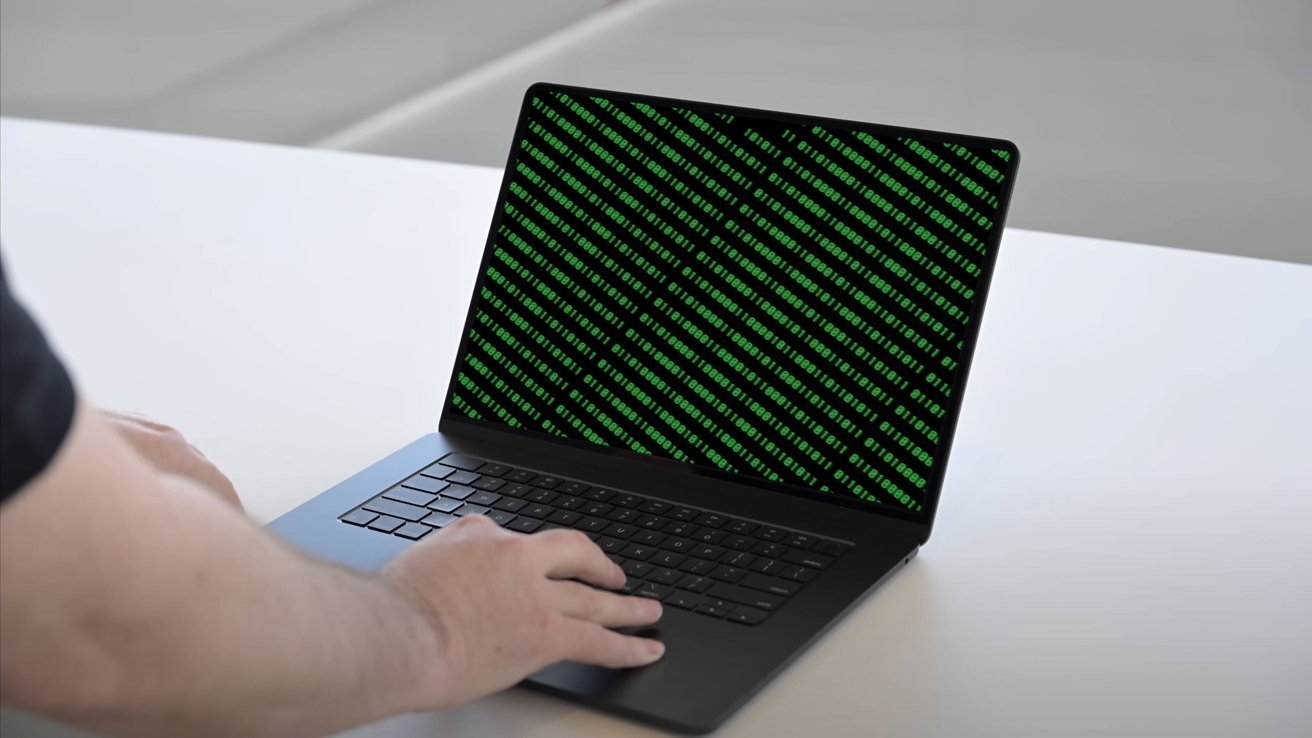 Ruka na klávesnici MacBooku s kódem na displeji