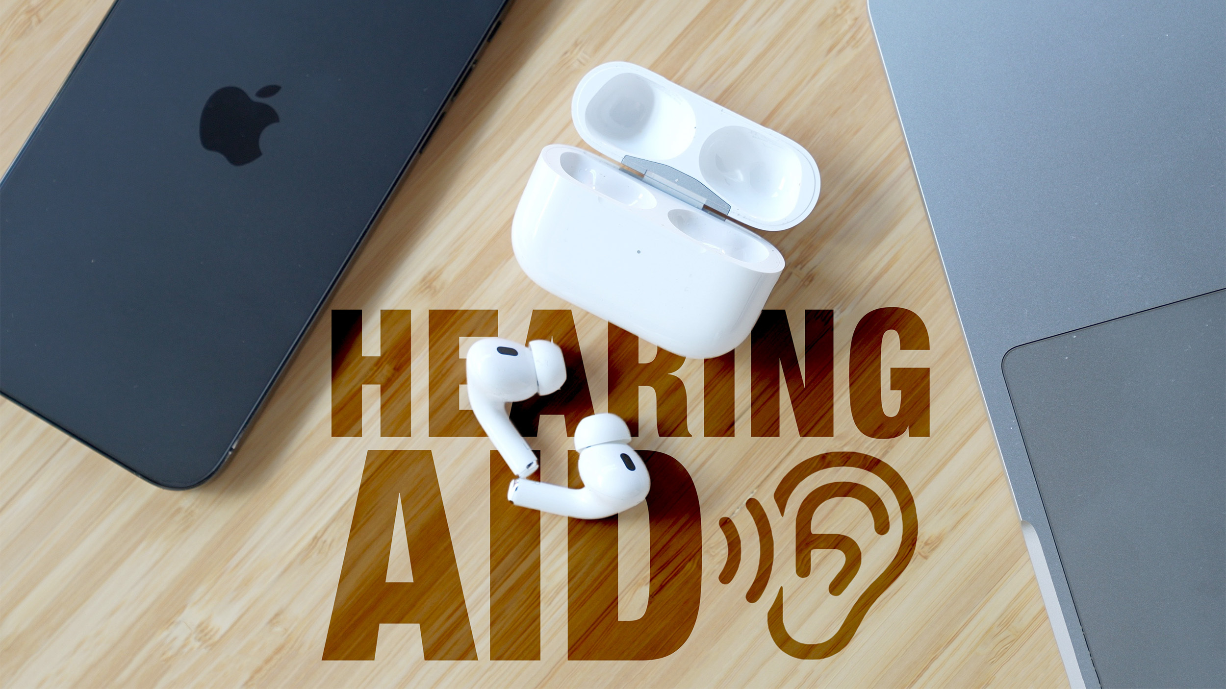 AirPods Pro v otevřeném pouzdře na stole vedle iPhonu a MacBooku
