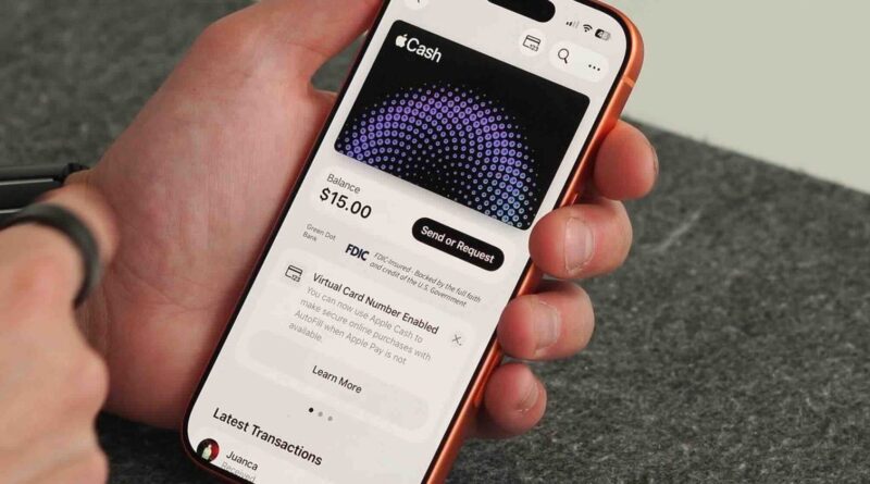 Ruka držící iPhone s otevřenou kartou Apple Cash v Peněžence