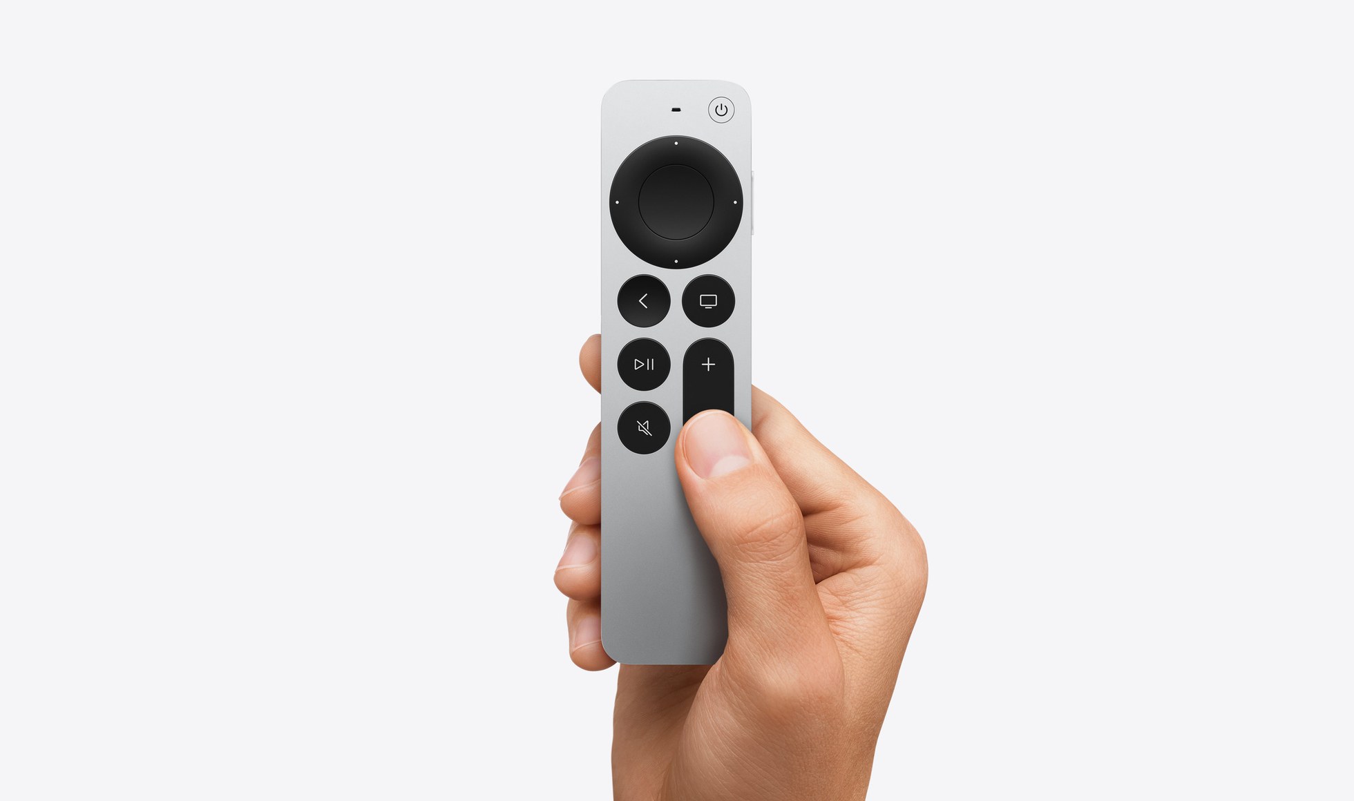 Ruka držící stříbrný ovladač Siri Remote