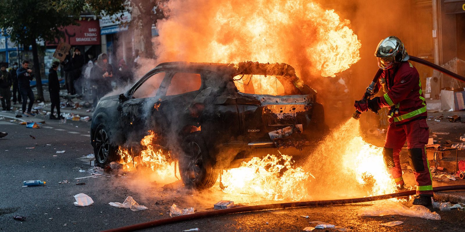 Hasič hasí hořící automobil během protestů ve Francii