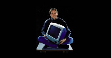 Steve Jobs sedící se zkříženýma nohama a původním počítačem iMac v klíně